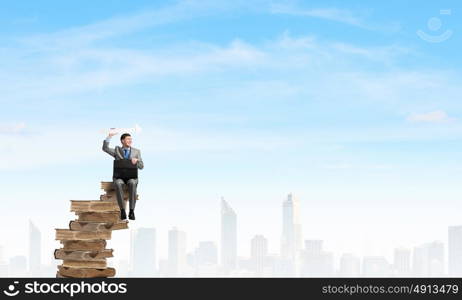 Businessman with suitcase. Young smiling businessman sitting with briefcase in hands