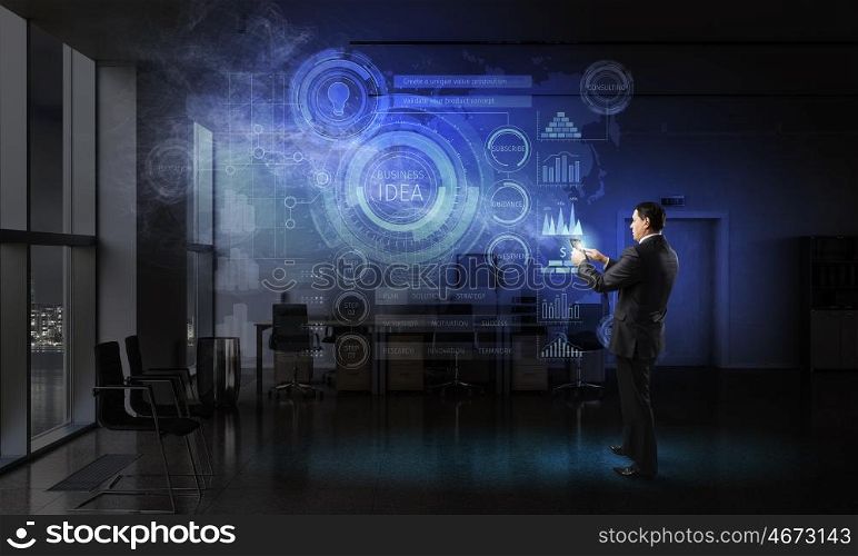 Businessman with tablet device in hands. Adult businessman in office dark interior using tablet pc