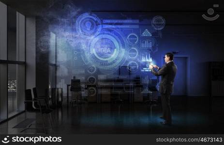 Businessman with tablet device in hands. Adult businessman in office dark interior using tablet pc