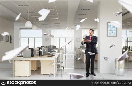 Businessman with tablet in hand. Adult businessman in modern office interior using tablet pc