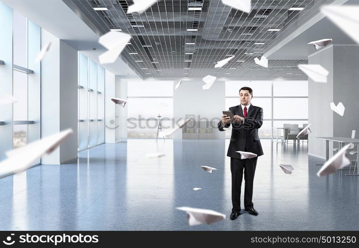 Businessman with tablet in hand. Adult businessman in modern office interior using tablet pc