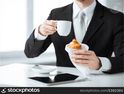 businessman with tablet pc, cup of coffee and croissant