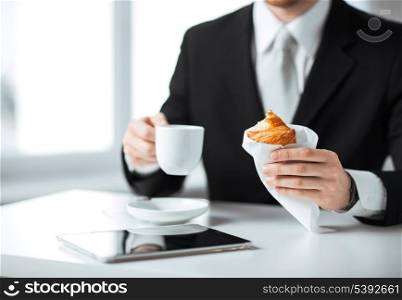 businessman with tablet pc, cup of coffee and croissant
