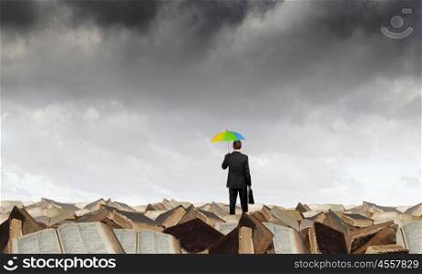 Businessman with umbrella. Businessman holding umbrella and waking on career ladder made of books
