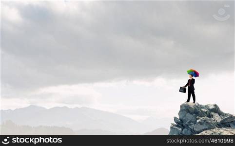 Businessman with umbrella. Businessman with umbrella and suitcase standing on mountain top