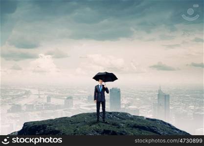 Businessman with umbrella. Businessman with umbrella and suitcase standing on mountain top