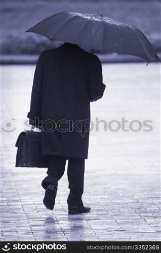 businessman with umbrella walking in the rain