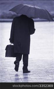 businessman with umbrella walking in the rain