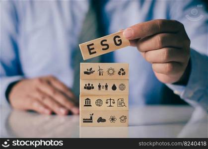 Businessman with wooden block on hand ESG icon concept for environmental, social and governance in sustainable and ethical business on network connection on green background.