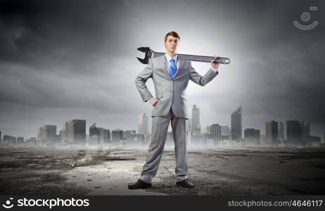 Businessman with wrench. Young determined businessman with wrench in hands