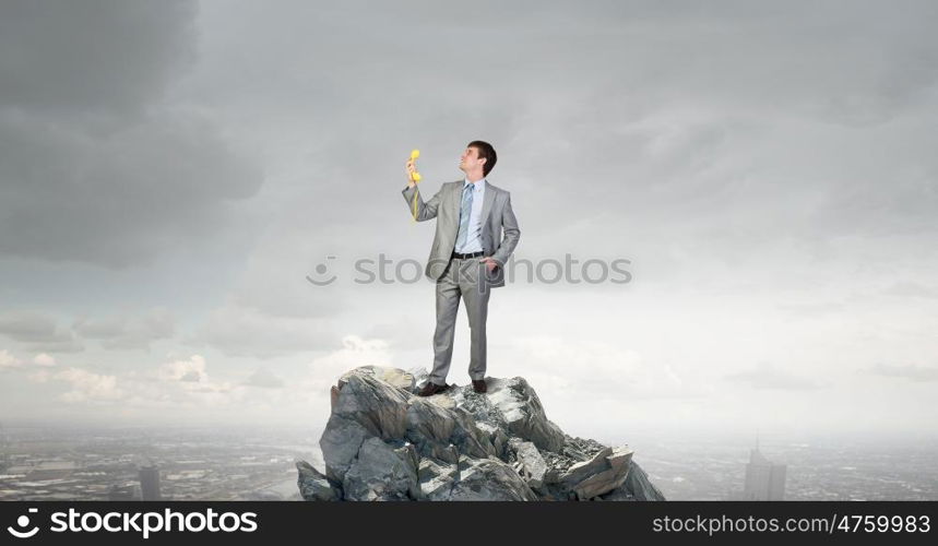 Businessman with yellow receiver. Handsome businessman talking on yellow phone handset