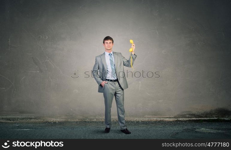 Businessman with yellow receiver. Handsome businessman talking on yellow phone handset