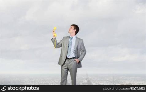 Businessman with yellow receiver. Handsome businessman talking on yellow phone handset
