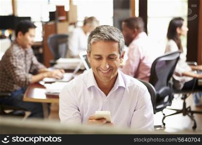 Businessman Working At Desk Using Mobile Phone