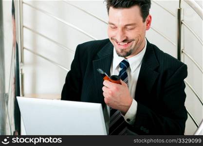 Businessman working at home with his laptop sitting on the stairs in his apartment