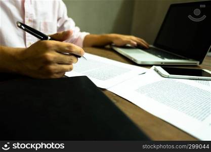 Businessman working at office with laptop and documents on the table, Businessman holding pens and papers taking notes in documents on the table.