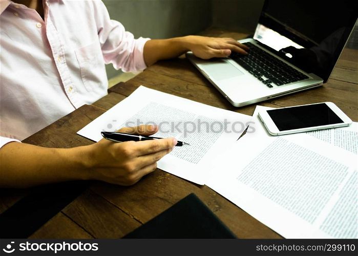 Businessman working at office with laptop and documents on the table, Businessman holding pens and papers taking notes in documents on the table.