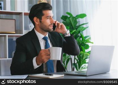 Businessman working in modern office workspace with cup of coffee in his hand while answering phone call making sales calls or managing employee. Fervent. Businessman making a sales call with clients with coffee at office. fervent