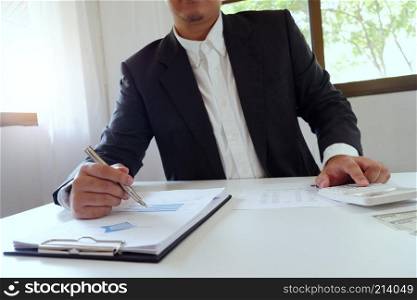 Businessman working in office using calculator with document on desk