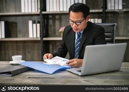 businessman working in the office. using laptop and taking notes on paper