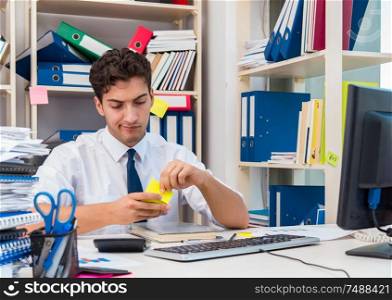 Businessman working in the office with piles of books and papers doing paperwork. Businessman working in the office with piles of books and papers