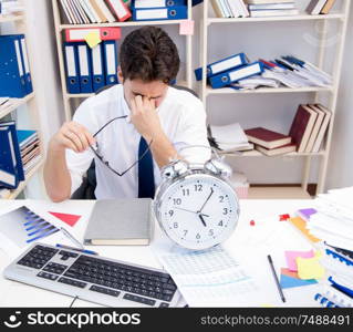 Businessman working in the office with piles of books and papers doing paperwork. Businessman working in the office with piles of books and papers