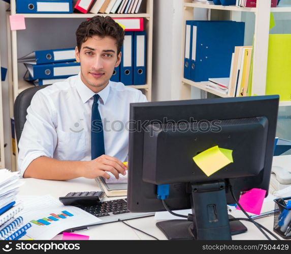 Businessman working in the office with piles of books and papers doing paperwork. Businessman working in the office with piles of books and papers