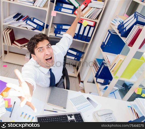 Businessman working in the office with piles of books and papers doing paperwork. Businessman working in the office with piles of books and papers