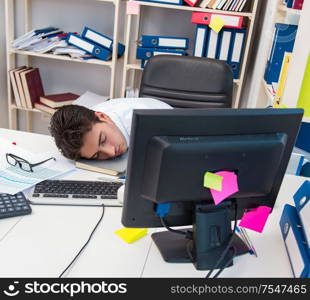 Businessman working in the office with piles of books and papers doing paperwork. Businessman working in the office with piles of books and papers