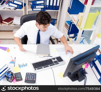 Businessman working in the office with piles of books and papers doing paperwork. Businessman working in the office with piles of books and papers