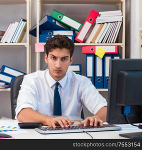 Businessman working in the office with piles of books and papers doing paperwork. Businessman working in the office with piles of books and papers