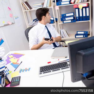 Businessman working in the office with piles of books and papers doing paperwork. Businessman working in the office with piles of books and papers