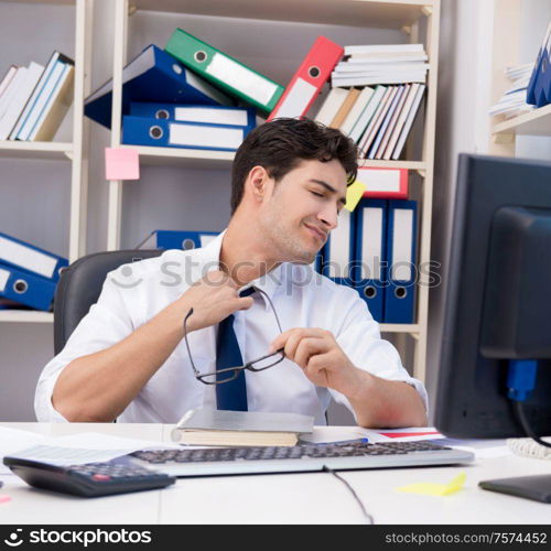 Businessman working in the office with piles of books and papers doing paperwork. Businessman working in the office with piles of books and papers