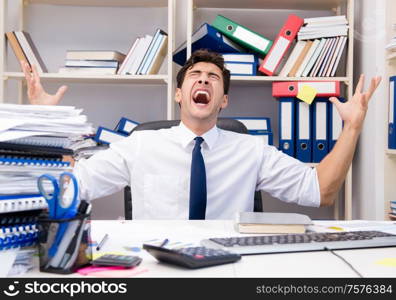 Businessman working in the office with piles of books and papers doing paperwork. Businessman working in the office with piles of books and papers