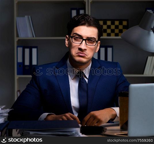 Businessman working late at night in office for overtime bonus. The businessman working late at night in office for overtime bon