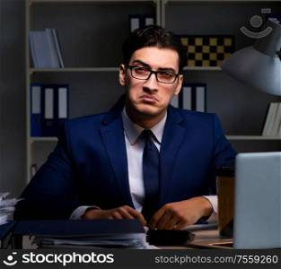 Businessman working late at night in office for overtime bonus. The businessman working late at night in office for overtime bon