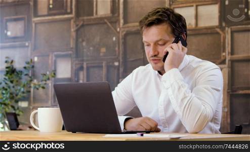 Businessman working on a laptop and talking phone in small business office for startup team. Man upset after unsuccessful negotiations. Looking sad and depressed because of mistakes.. Businessman working on laptop and fails