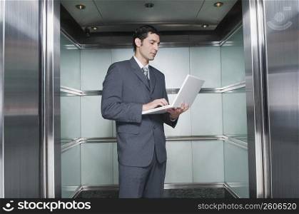 Businessman working on a laptop in an elevator