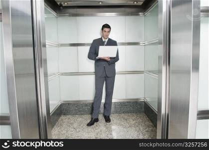 Businessman working on a laptop in an elevator