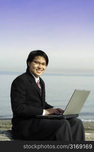 Businessman working on his laptop at the beach