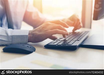 Businessman working on keyboard and mouse computer man sitting on the table and using internet technology at workplace in office / Close up of typing male hand on keyboard concept
