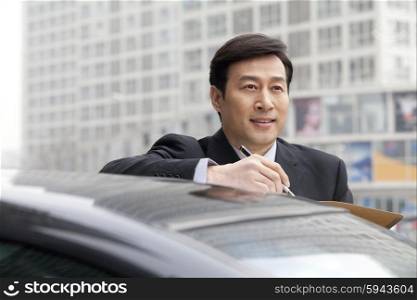 Businessman working outdoors on car