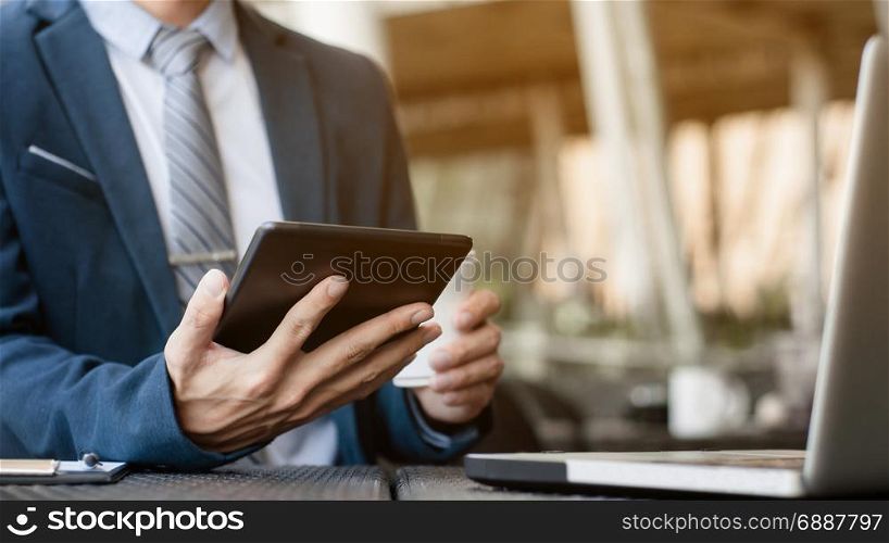 businessman working with digital tablet and laptop with financial business strategy at a coffee shop cafe