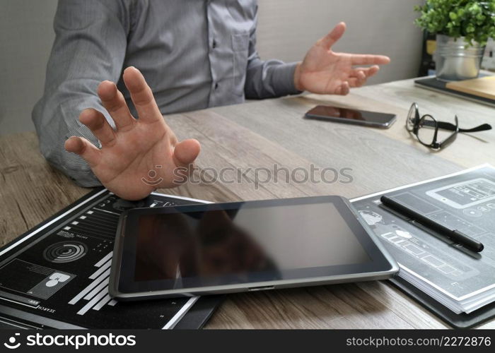 businessman working with digital tablet computer and smart phone and laptop computer with financial business strategy layer effect on wooden desk