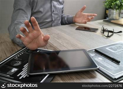 businessman working with digital tablet computer and smart phone and laptop computer with financial business strategy layer effect on wooden desk