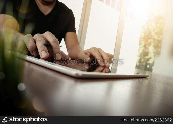 businessman working with digital tablet computer on wooden desk with green plant foreground as concept
