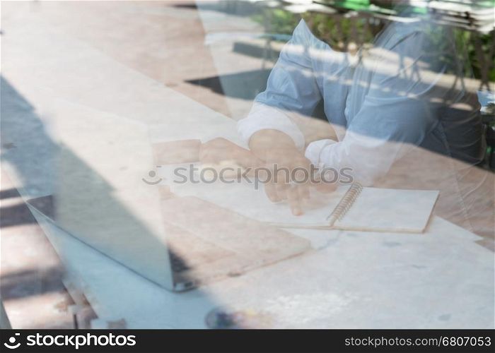 businessman working with document and laptop computer in office workplace - seen through glass blur for background
