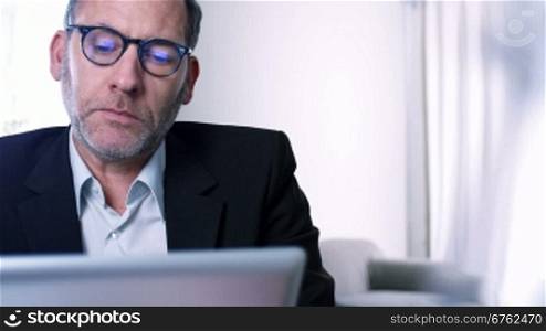 Businessman working with tablet PC / ipad in his office or Hotel room - tracking shot