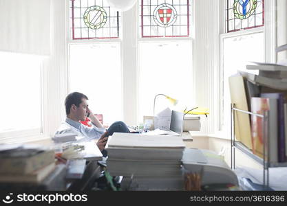 Businessman works from desk in bay window