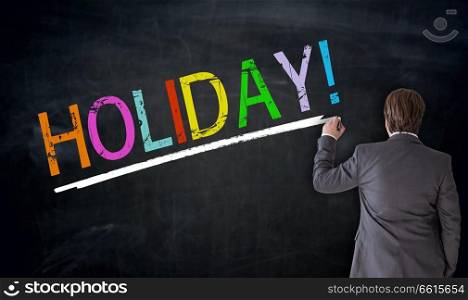 Businessman writes Holiday on blackboard concept.. Businessman writes Holiday on blackboard concept